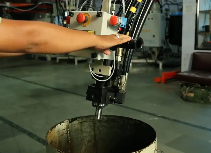 Operator's hand guiding a dispensing head over a drum