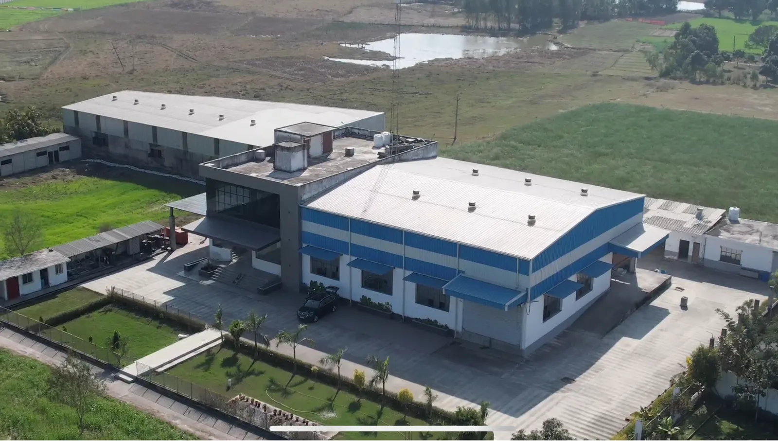 The plant from above — blue-roofed sheds in green fields