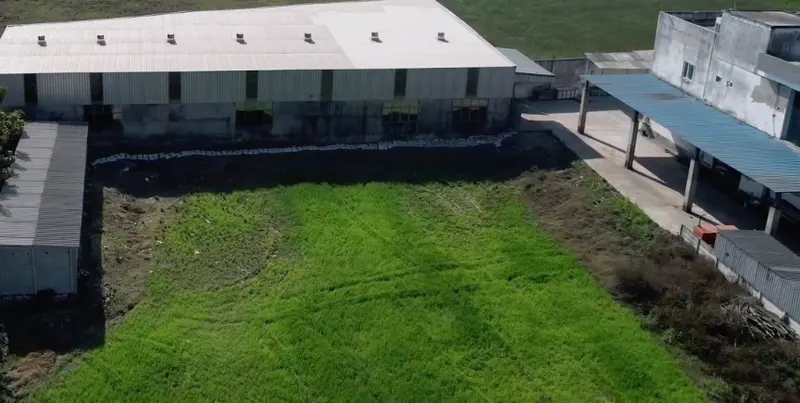 A production shed behind a green field