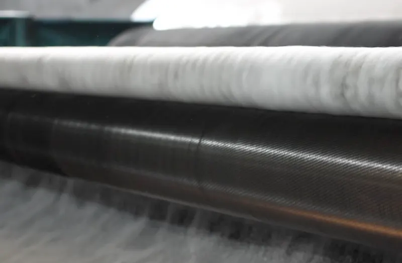 Non-woven fibre web running over a roller on the bonding line