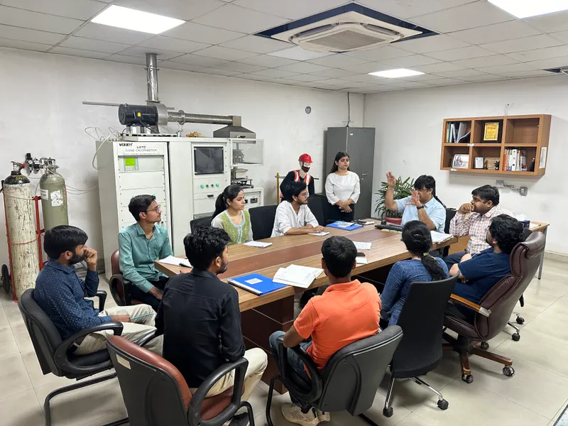 The team in discussion around a conference table, test equipment behind